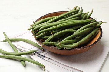 Fresh pea pods, napkin and bowl on white table, closeup
