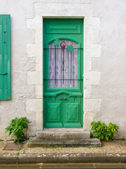 Green door with overhanging grape cluster and leaves ornaments.