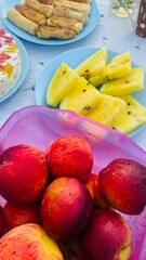 Summer Picnic Table with a Basket of Fresh Peaches and Nectarines. Plates of Yellow Watermelon and Pancakes in the Background