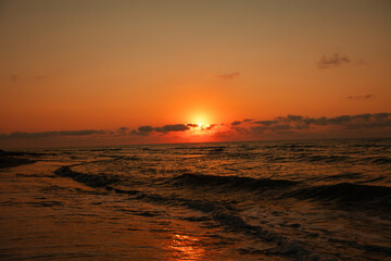 Dramatic sunset over the sea with orange sky and waves