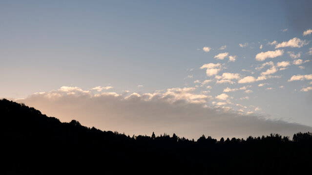 Evening orange sunset behind the mountains, clouds