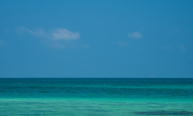 Photography peaceful tropical sea beach with soft white sand, turquoise sea, and small island in distance under bright blue sky with fluffy clouds. scene for summer vacation travel and relaxation.