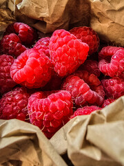 Fresh ripe raspberries in kraft paper packaging, close-up. Natural farm product, organic berry.