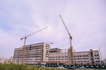 Unfinished construction building site with cranes and new residential apartments. Urban development...