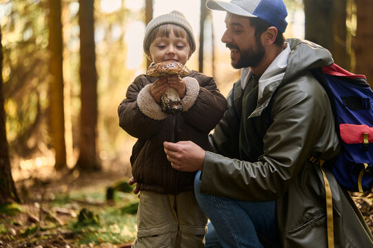 Father and son admiring forest mushroom together