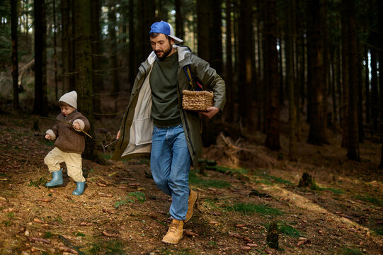 Father helping son in forest while foraging mushrooms