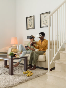 Diverse women playing VR video games in living room