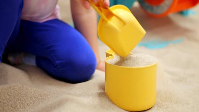 Child playing with sand and yellow bucket