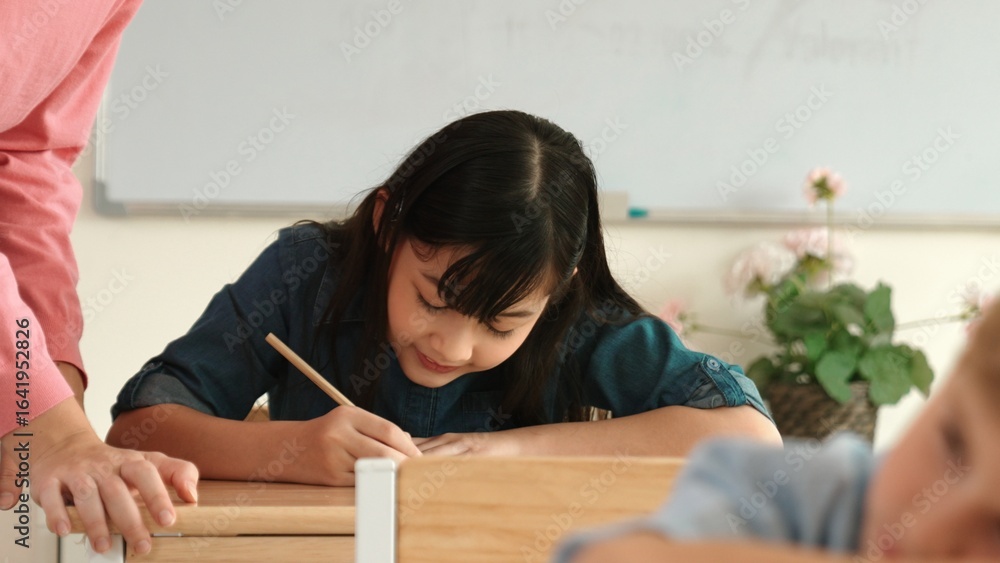 Poster asian girl writing or taking a note while teacher checking classwork. caucasian teacher help happy s