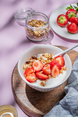 Granola or muesli with natural greek yogurt, strawberry and honey in a bowl on a wooden board