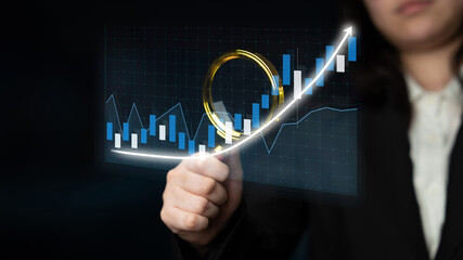 A businessperson analyzes a financial data trend with a graph and chart against a dark background,...