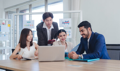 Diverse group professionals meeting collaborating modern office environment team gathered around table utilizing laptop tablet discuss business strategies analyze data. background display chart graph