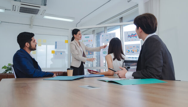 Business manager employee teamwork asian group meeting presentation look holding document computer on desk labtop talk project creative plan ready for happy work marketing online sale in room office - Powered by Adobe