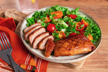 Delicious grilled duck breast served with fresh garden salad and cherry tomatoes at a rustic dining...