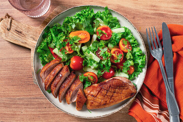 Delicious grilled duck breast served with fresh garden salad and cherry tomatoes at a rustic dining table