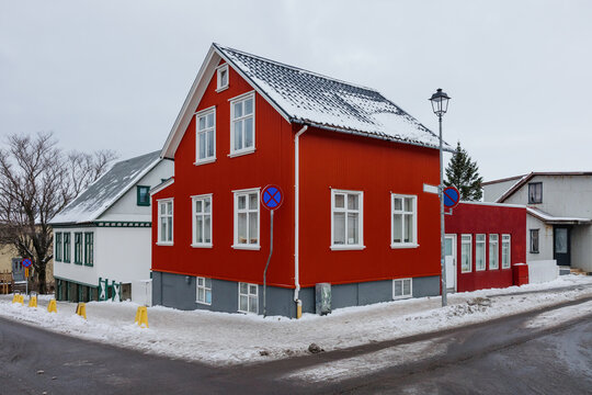 Fototapeta Red wooden house on snowy urban street corner