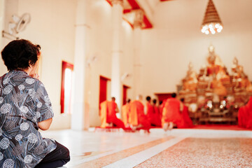 A meditative scene featuring old woman and Buddhist monks in orange robes conducting a serene...