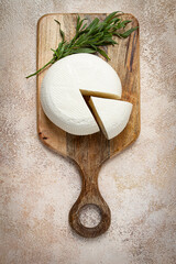 Head of Georgian cheese, Imereti variety, top view, on a cutting board,
