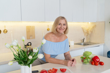 A joyful senior woman prepares delicious meals with fresh ingredients in her stylish kitchen,...