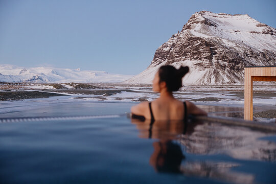 Woman relaxing in hot spring with snowy mountain view - Powered by Adobe