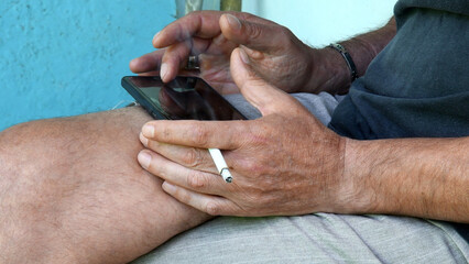 Asian man hands with cigarette and phone tapping by finger