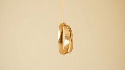 Three golden wedding bands suspended vertically against a soft beige backdrop.