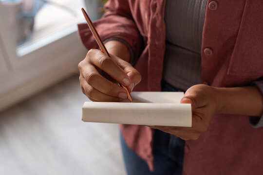 Woman Writing Notes in a Notepad Indoors During Daylight Hours