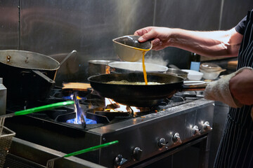 Chef cooks over big Open flames on a stove  