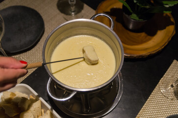 Traditional cheese fondue with bread and a glass of wine.