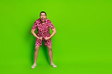 Young man in vibrant leopard print outfit against green background showcasing cheerful and energetic emotions with a summer vibe