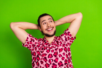 Joyful young man in a pink leopard shirt in front of a vibrant green backdrop, exuding positivity...