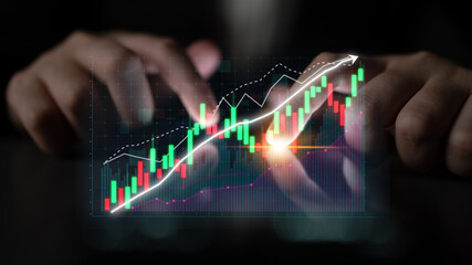 Close-up view of hands manipulating digital financial graphs, showcasing stock market trends with...