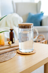 Homely atmosphere. Carafe of water, an aloe houseplant, an aroma diffuser, and a candle on a coffee table in the living room.