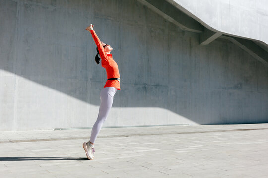 Person performs a joyful leap against a minimalist gray structure