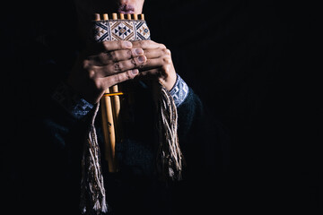 Andean man playing the flute and panpipe, traditional musical instruments of the Andes, with a...