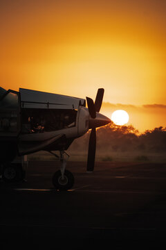 Small turboprop aircraft on tarmac at sunrise