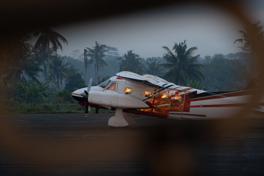 Small twin-engine piston aircraft on tarmac at dawn, framed view