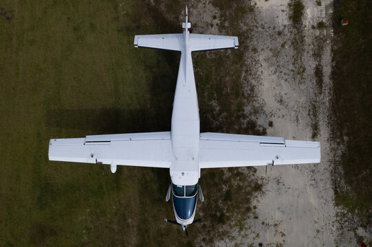 Top-down view of a single-engine turboprop aircraft on grass airstrip
