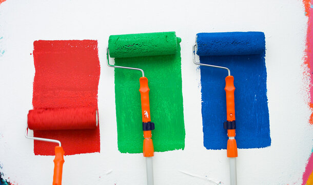 RGB color transition. Paint rollers applying vibrant hues on a wall