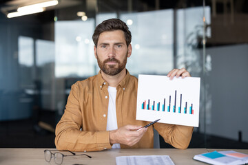 Confident office worker showcasing a statistical chart in a modern workplace environment, expressing data-driven insights. The visuals blend professionalism, analysis, and business decision-making