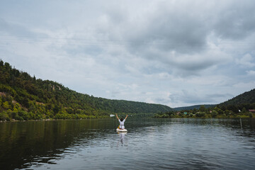 A joyful person kayaks gracefully across a tranquil lake, surrounded by lush hills and a radiant...