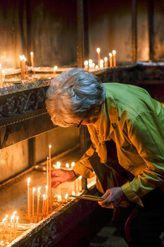 Elderly Woman Lighting a Candle in Church
