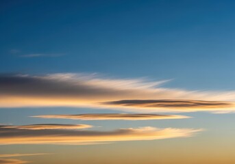 Obraz premium Beautiful layered clouds with golden light at sunset in a clear blue sky