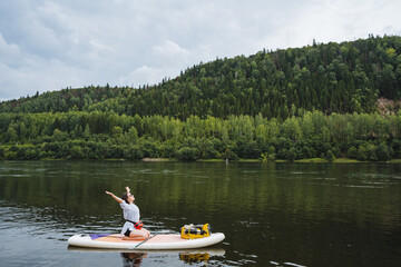 An adventurer showcases impressive paddleboarding skills on a tranquil river, surrounded by lush...
