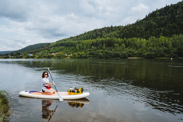 Enjoy a serene paddleboarding adventure on a picturesque lake surrounded by lush hills and calm waters, perfect for outdoor enthusiasts and nature lovers seeking tranquility and enjoyment