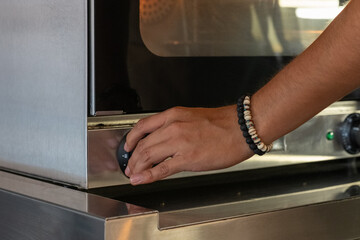 Baker adjusting settings on a professional oven while baking