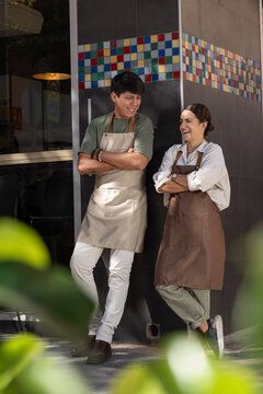 Laughing waitress and barista standing near cafe