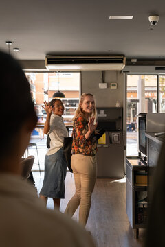 Happy clients waving hands to cafe workers