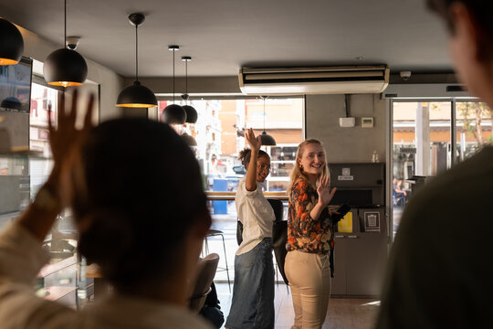Happy cafe guests waving hands to owners while leaving