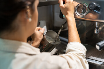 Anonymous barista steaming milk in pitcher
